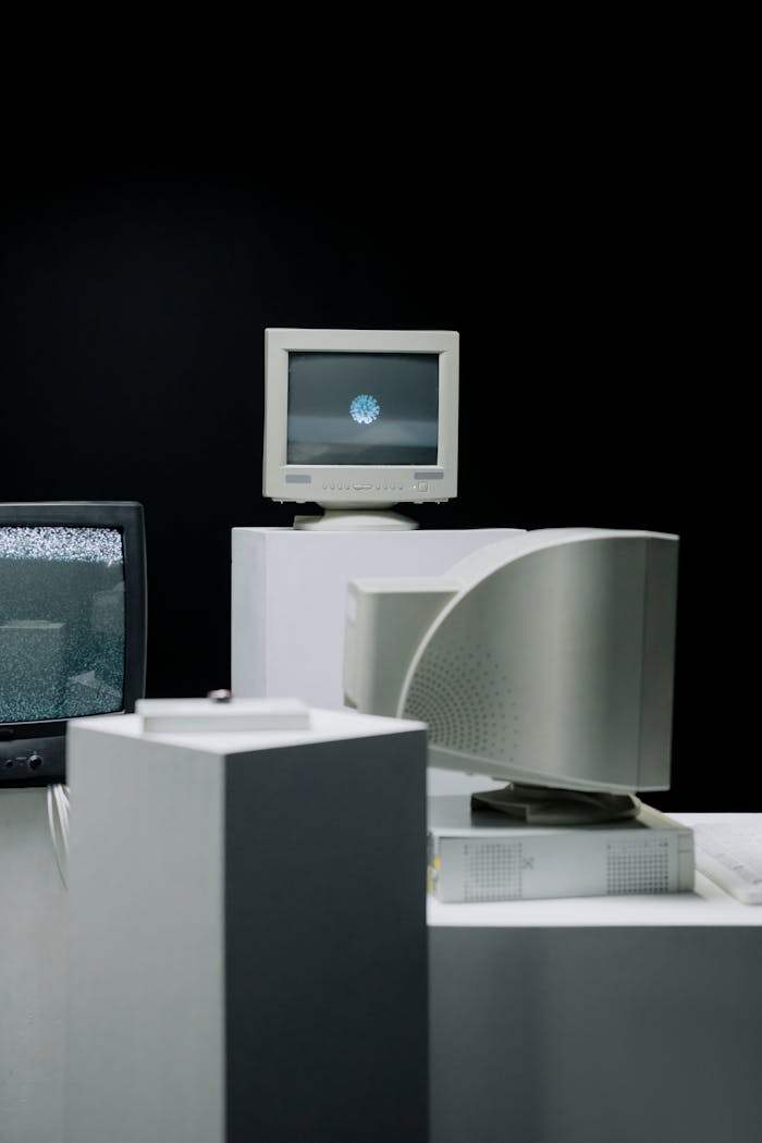 Vintage computer monitors arranged in a minimalist setup with a dark background, showcasing technology evolution.